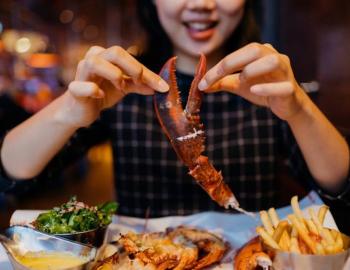 woman eating a lobster claw at dinner